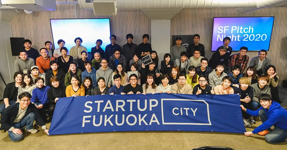 Orang-orang berkumpul membawa bendera STARTUP CITY FUKUOKA